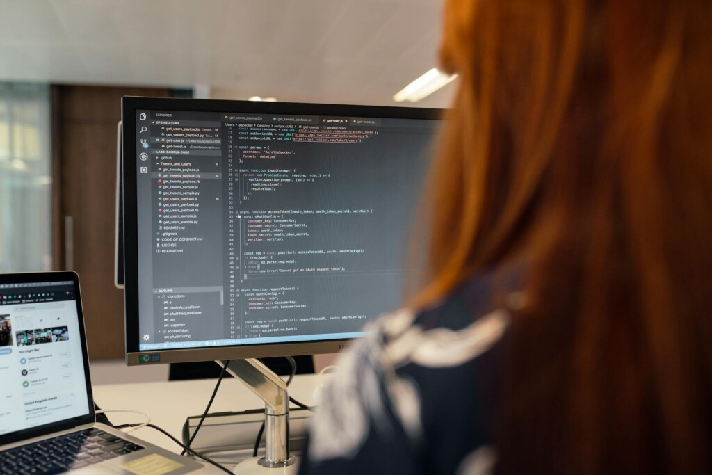 Ingénieur en informatique analysant du code sur plusieurs écrans dans un open space moderne