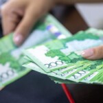 Main posant des billets d'euros sur un livret d'épargne bancaire ouvert