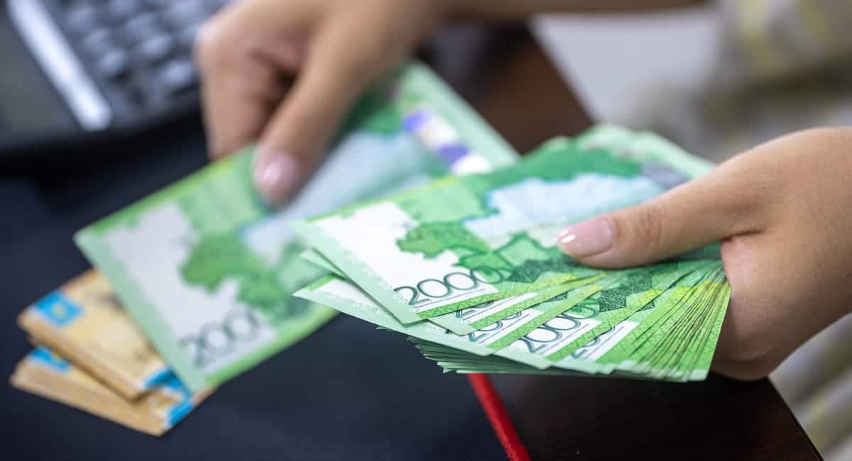 Main posant des billets d'euros sur un livret d'épargne bancaire ouvert