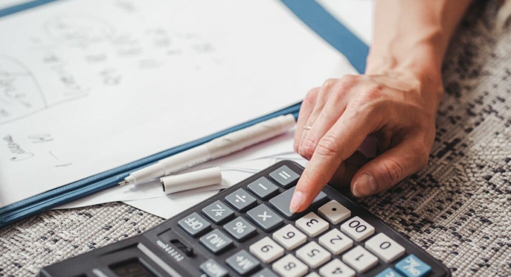 Entrepreneur calculant la TVA sur une facture avec calculatrice