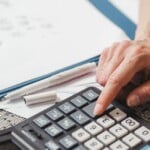 Entrepreneur calculant la TVA sur une facture avec calculatrice