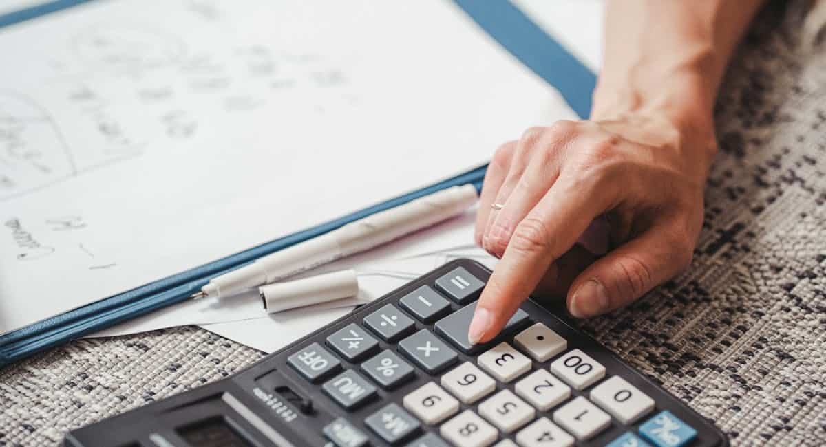 Entrepreneur calculant la TVA sur une facture avec calculatrice