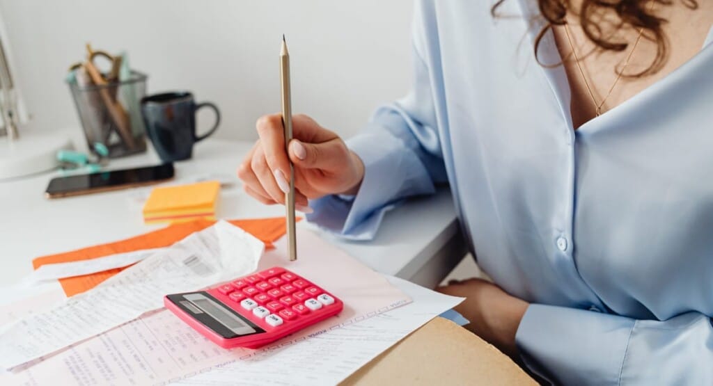 Auto-entrepreneur devant un ordinateur avec documents fiscaux et budget