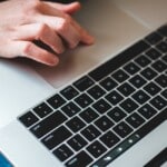 Main posée sur un clavier d'ordinateur consultation espace bancaire en ligne