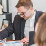 Un entrepreneur analyse des dossiers devant des plans d'immeubles et des graphiques